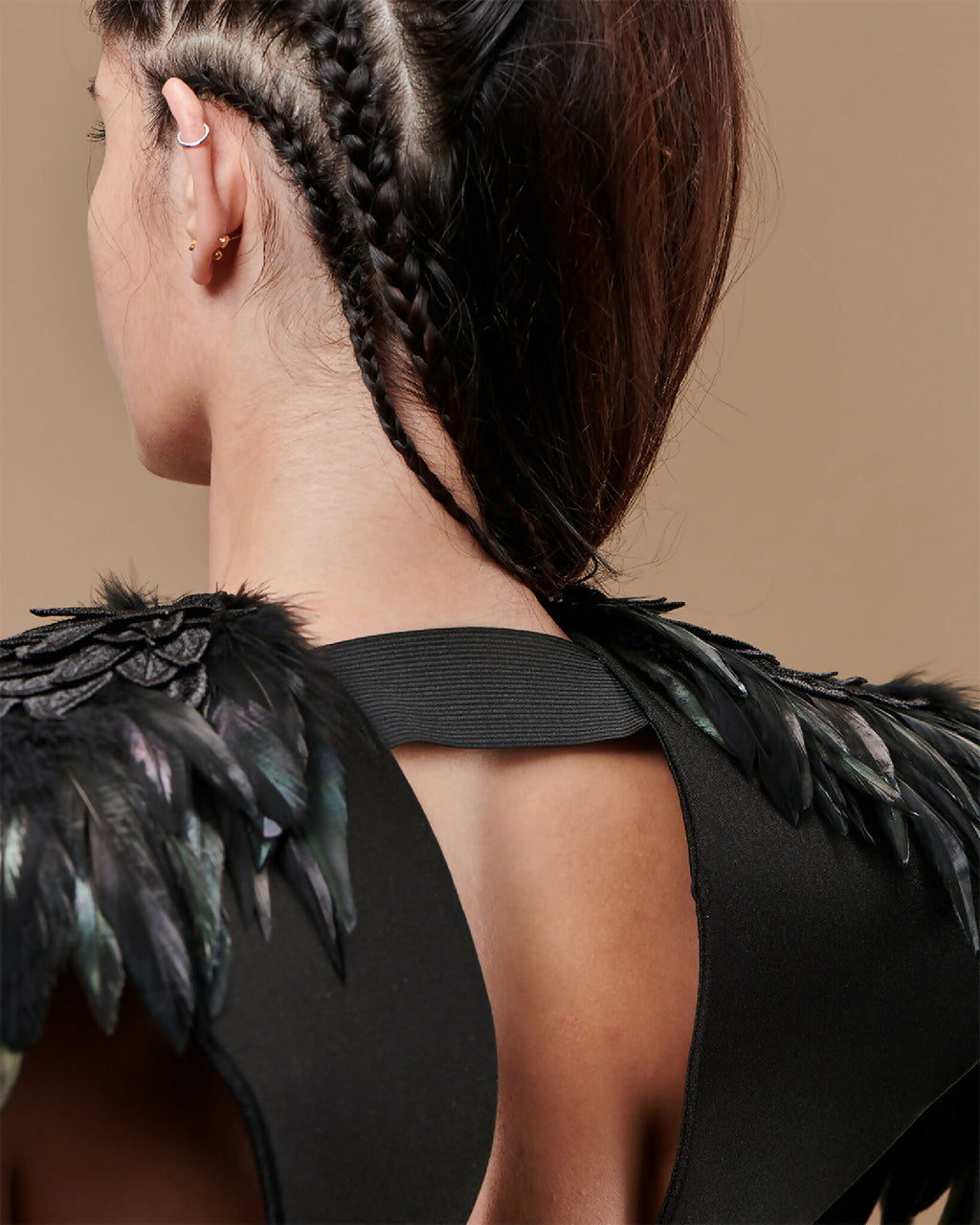Épaules en plumes noires à reflets vert, sangle noire et crochet sur l’épaule