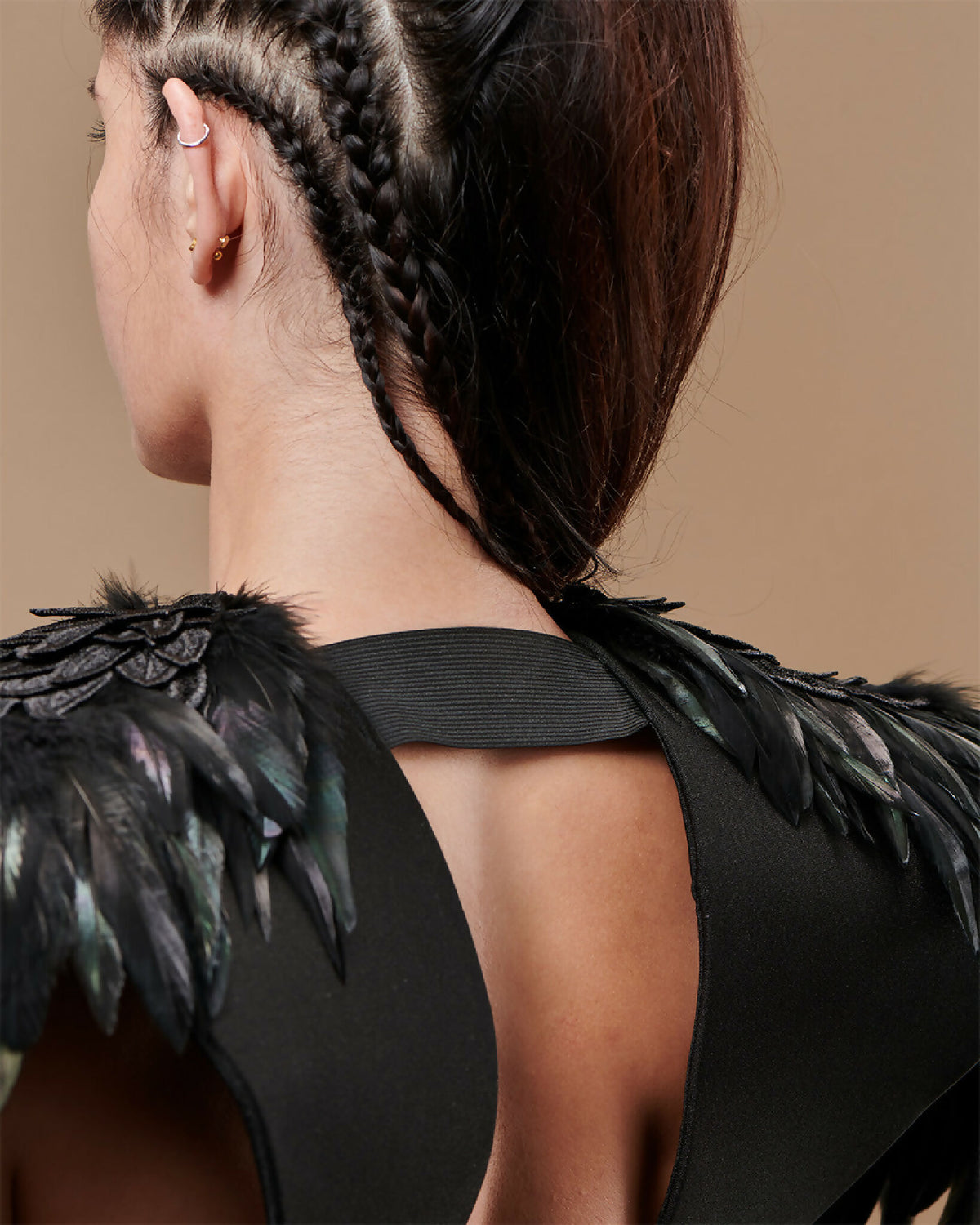 Épaules en plumes noires à reflets vert, sangle noire et crochet sur l’épaule