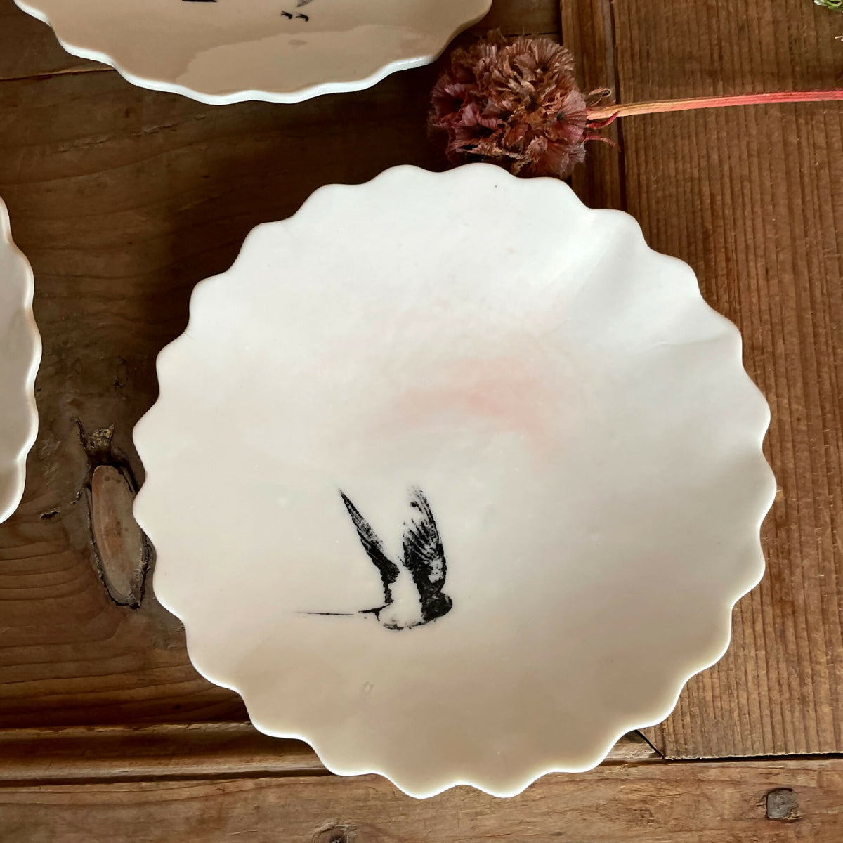 Coupelle en porcelaine blanche bord festonné, oiseau noir en plein vol, décor peint