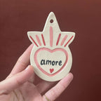 Ex-voto en forme d’étoile, cœur « amore » rose, traits et étincelles colorés.