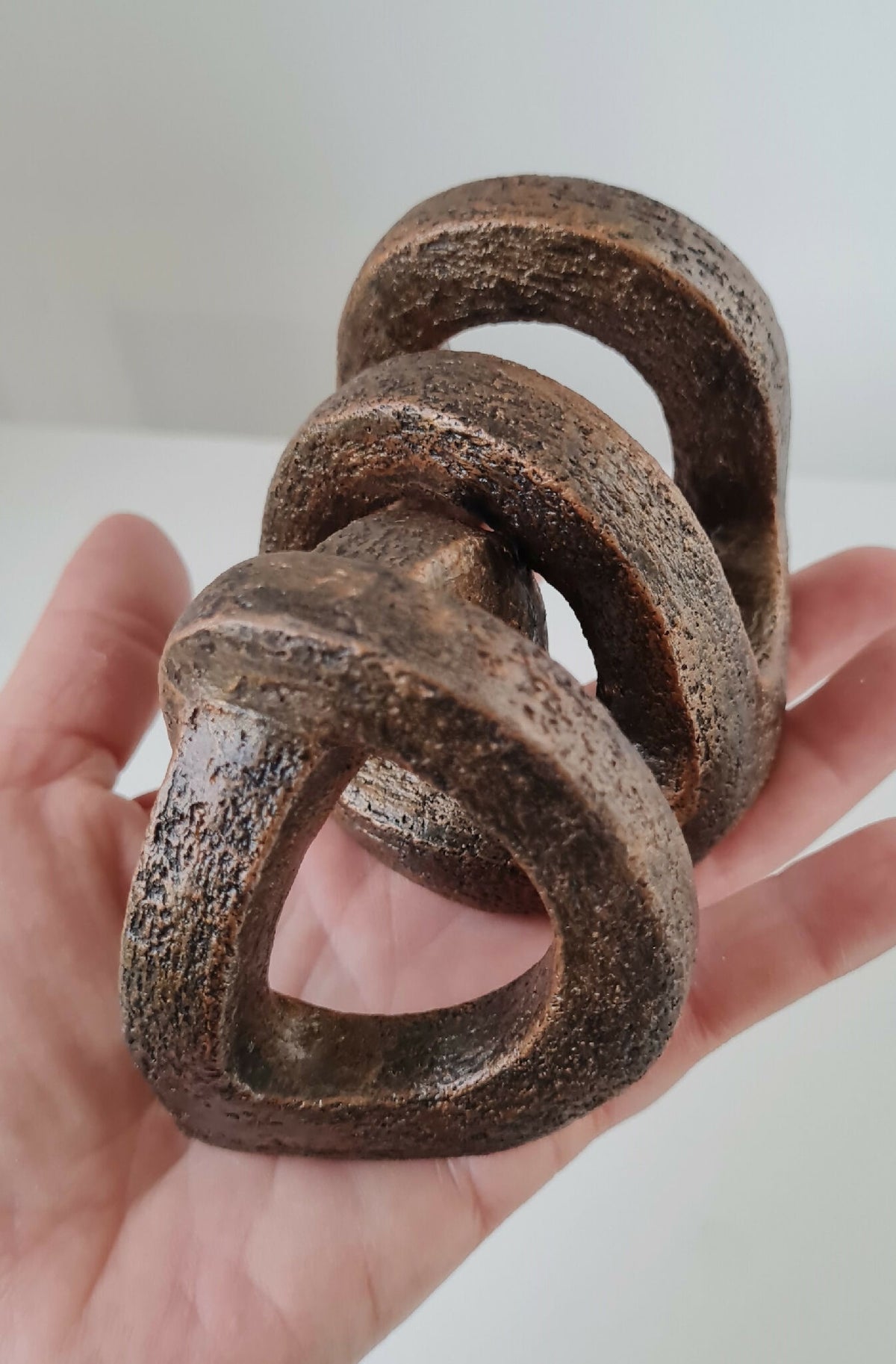 Sculpture abstraite brun foncé, anneaux entremêlés ajourés, vue rapprochée