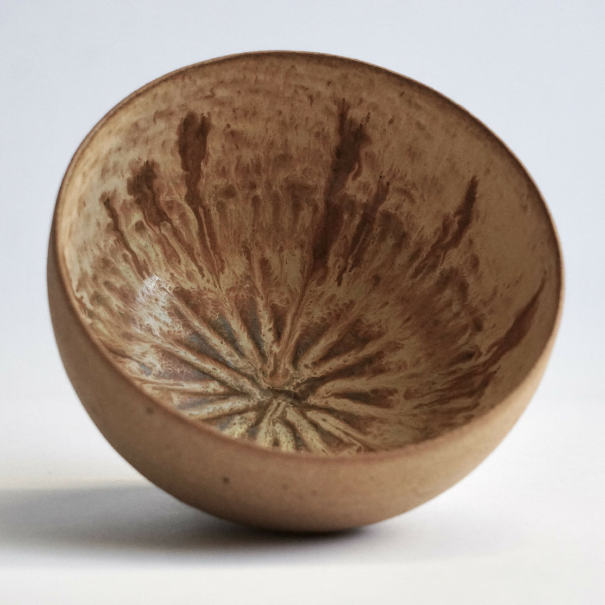 Bol en grès beige avec motif gravé au centre, vue de dessus.