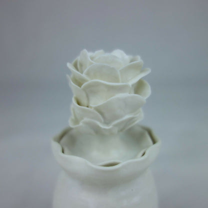 Vase en céramique blanc, gros plan des fleurs en relief au sommet.
