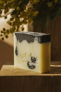 Savon au patchouli et charbon végétal, cube blanc avec dessus gris foncé.