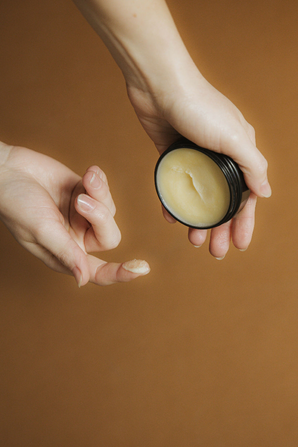 Baume solide appliqué avec le doigt, crème jaune pâle dans un petit pot
