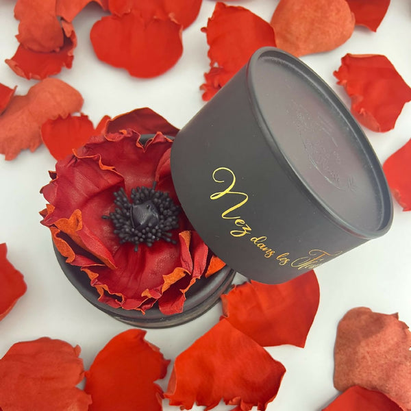 Bougie cylindrique noire « Nez dans les Fleurs », couvercle ouvert, fleurs rouges.