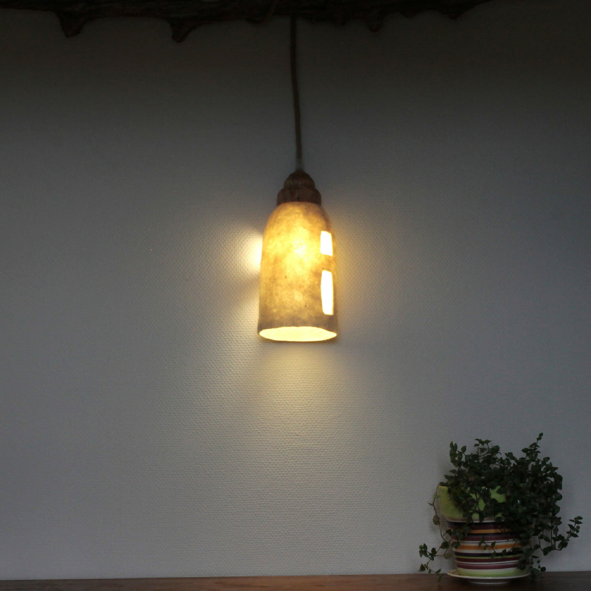 Lampe baladeuse allumée, abat-jour en feutre clair avec ouvertures découpées, lumière chaude