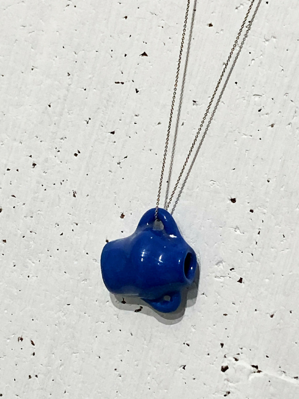 Pendentif en porcelaine bleue de forme irrégulière sur chaîne en argent.