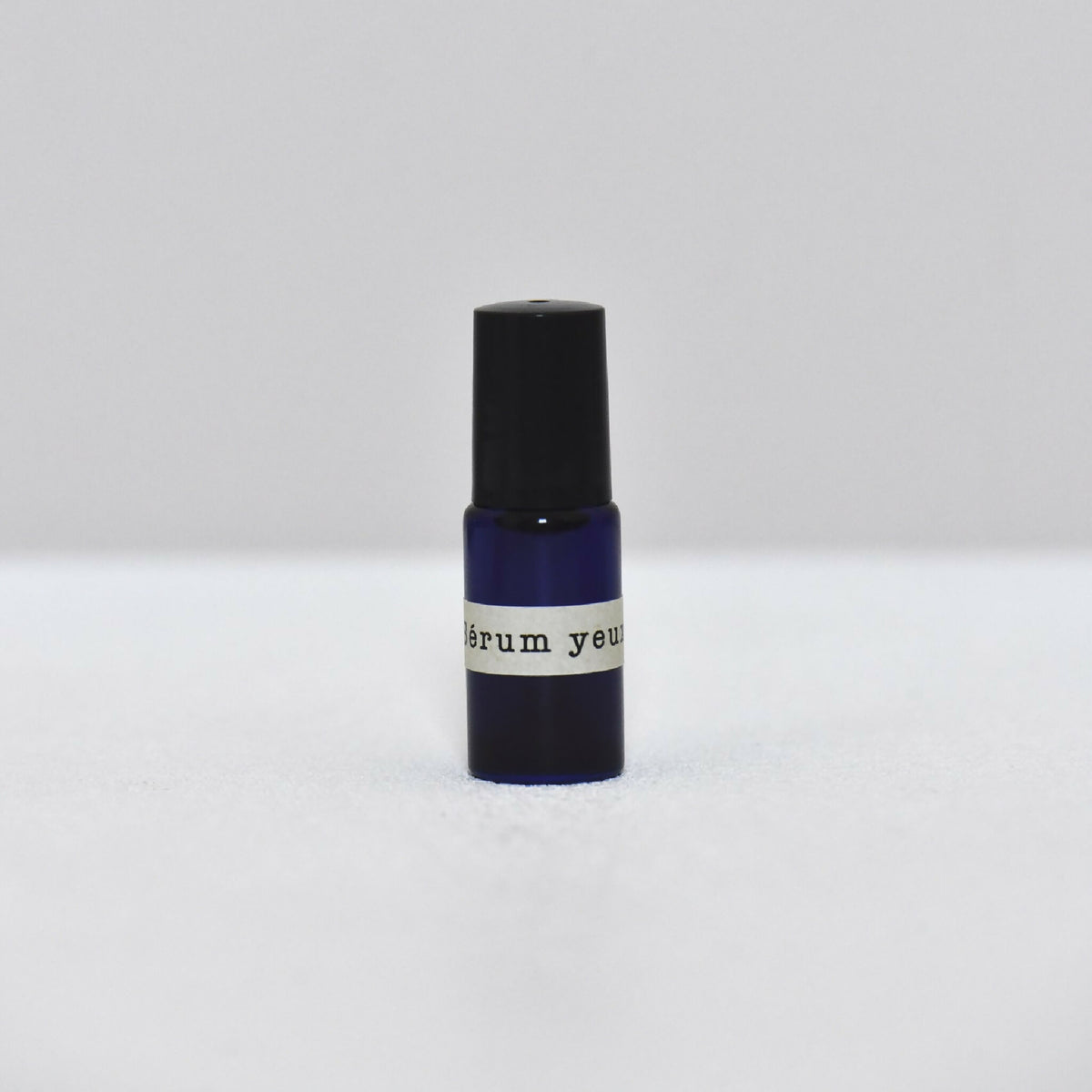 Flacon de sérum pour les yeux avec bouchon noir et base bleu foncé
