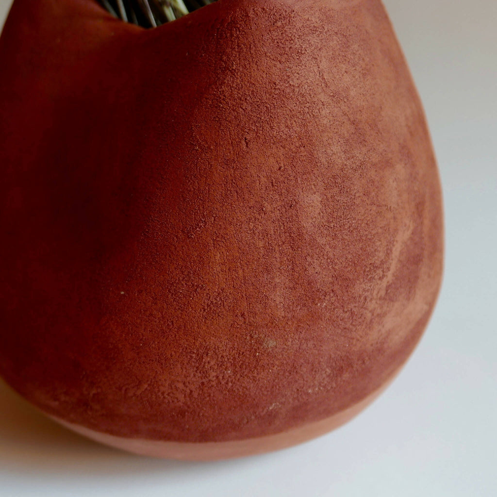 Vase en céramique rouge BRAZIL, gros plan sur la texture mate et la courbure.