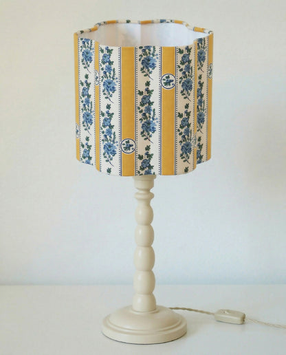 Abat-jour forme fleur en tissu rayé jaune et bleu, sur pied blanc à boules.