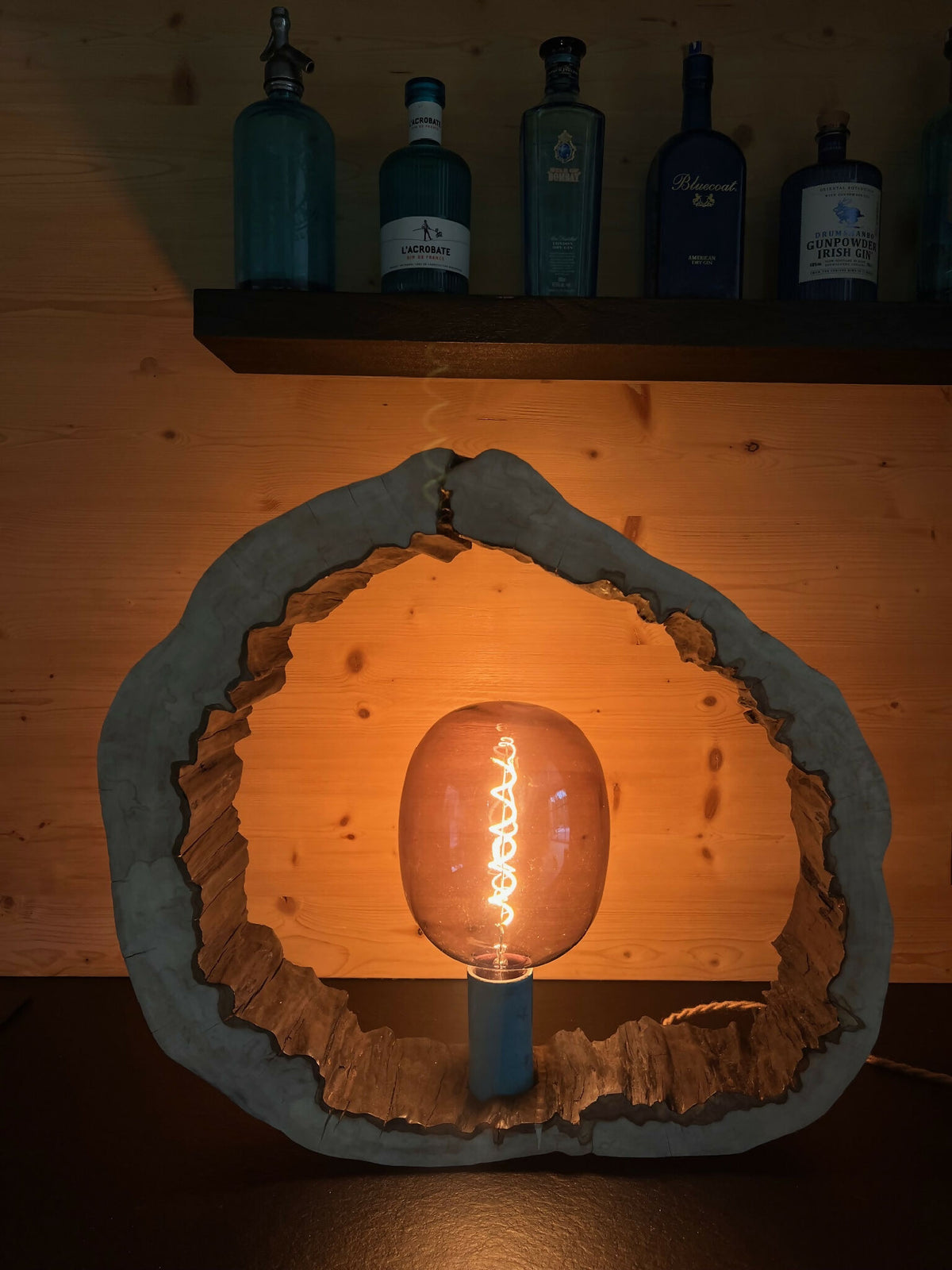 Sculpture lumineuse murale en forme d’anneau, ampoule éclairée et socle cylindrique bleu