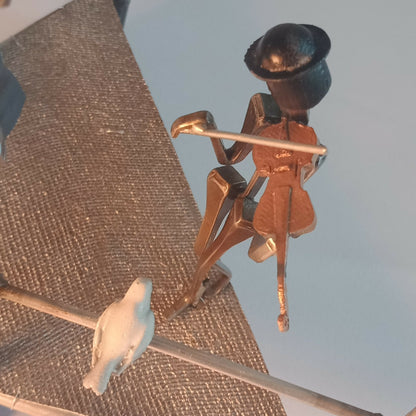 Danseuse en métal doré et chapeau noir sur manège décoratif, avec oiseau en blanc.