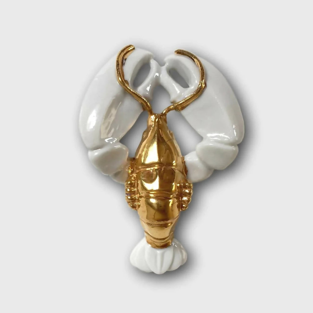 Porte-couvert homard blanc et doré, forme de pinces et queue décoratives.