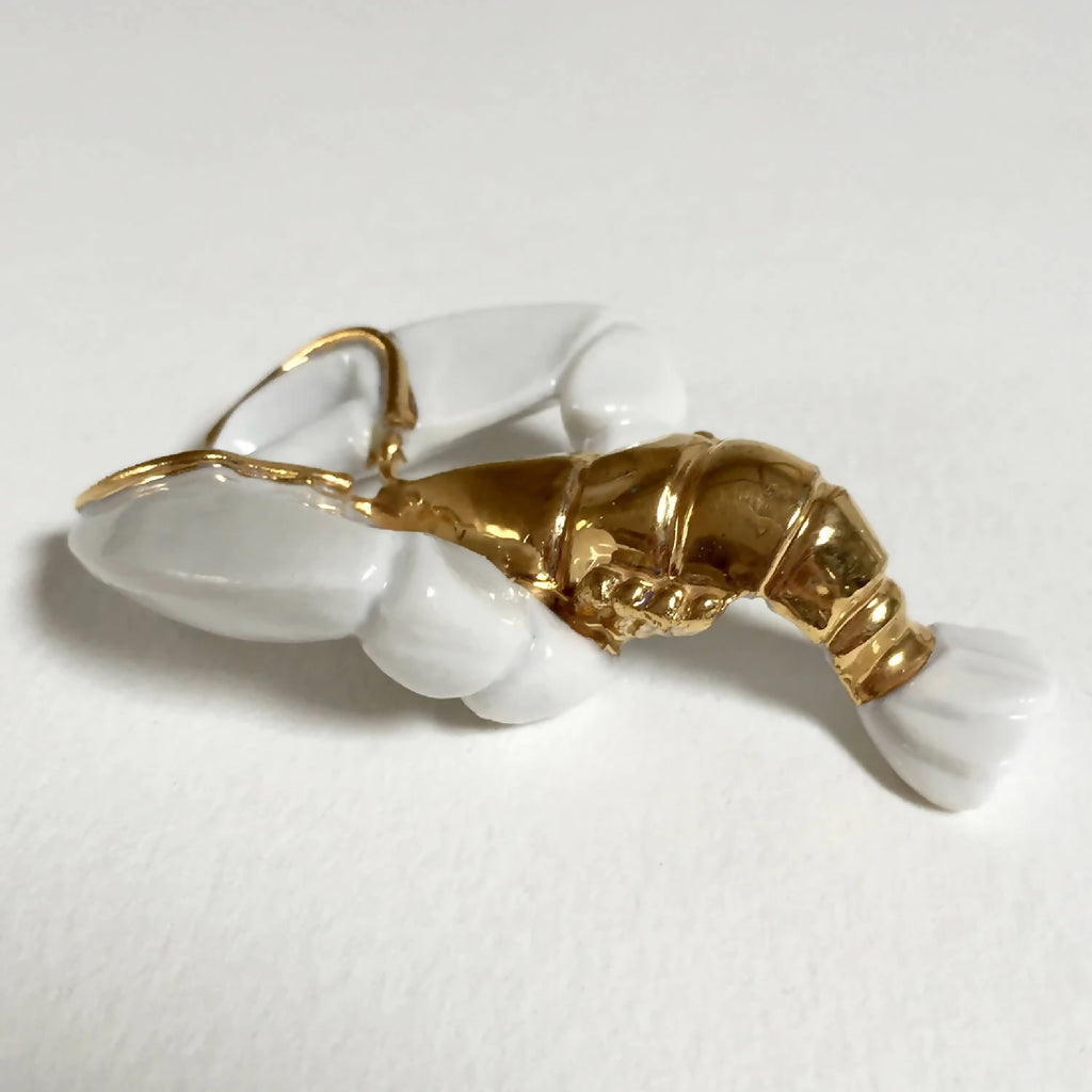 Porte-couvert homard doré avec pinces blanches, vue de profil.