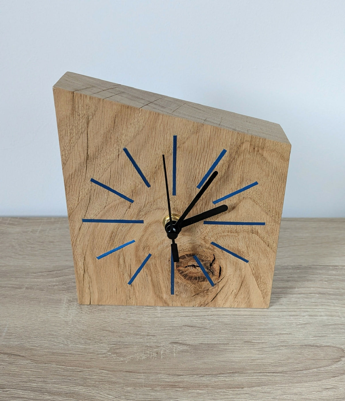 Horloge de bureau en bois clair, cadran bleu, aiguilles noires, vue de face.