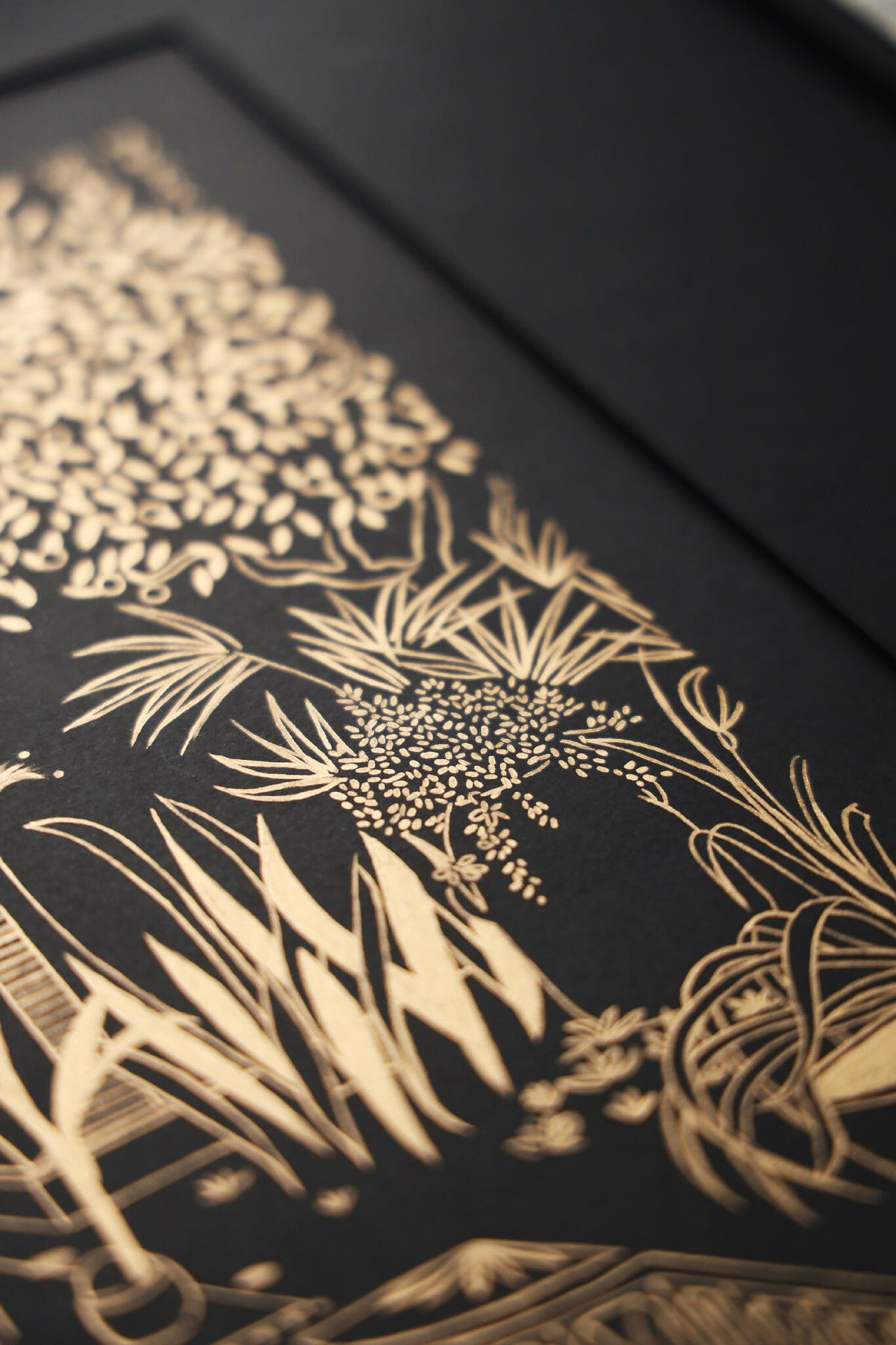 Détail de sérigraphie : motifs floraux et lignes dorées sur fond sombre