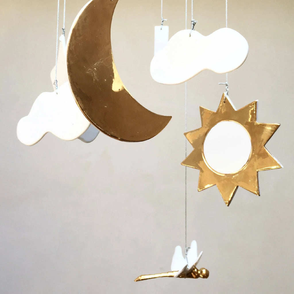 Mobile de naissance : gros plan lune dorée, étoile dorée et nuages blancs pendants.