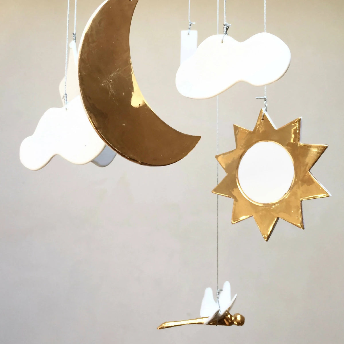 Mobile de naissance : gros plan lune dorée, étoile dorée et nuages blancs pendants.
