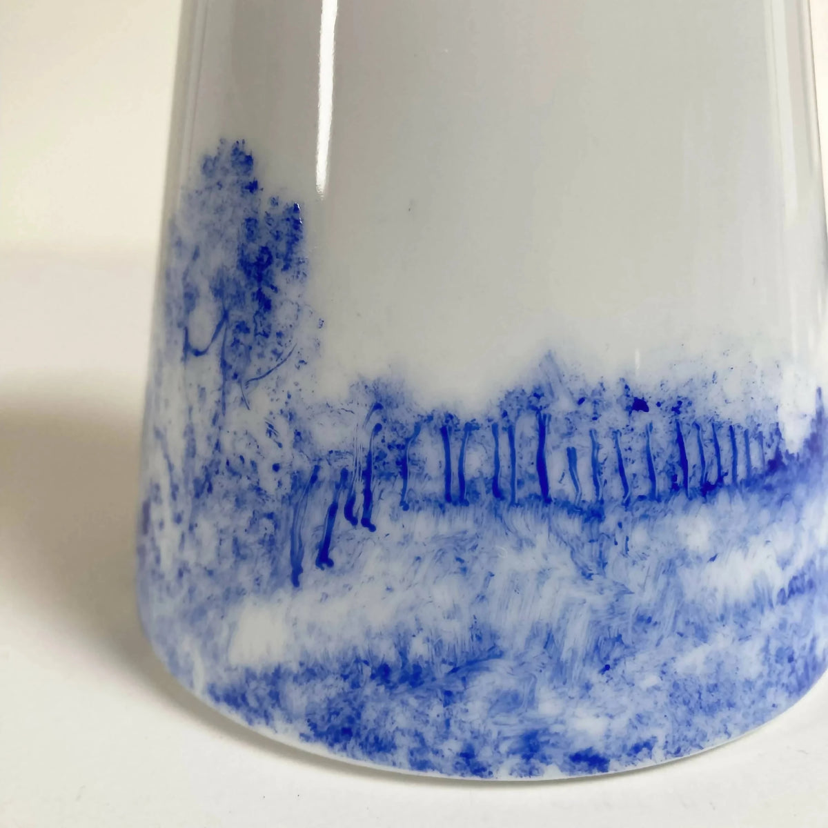 Pichet à lait en céramique blanc, gros plan sur le motif bleu paysage