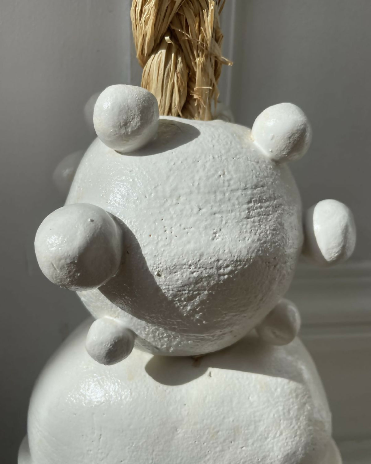 Figurine blanche en relief avec bras et tête ronde, fixée au cordage