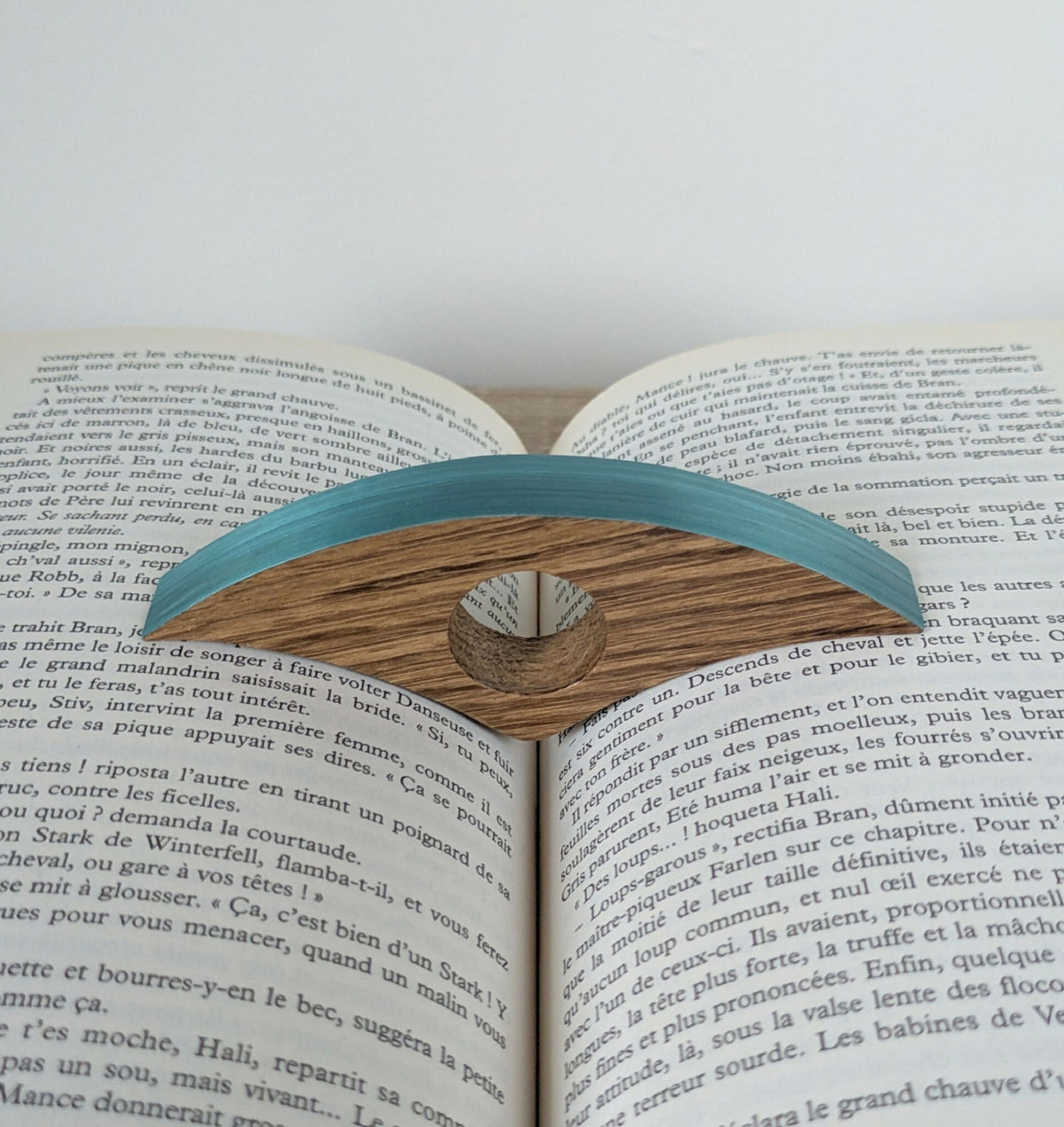 Marque-page en bois bleu turquoise sur livre ouvert, motif ajouré