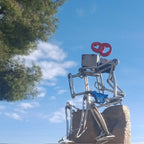 Sculpture en fils d’acier sur socle doré, couple et cœur rouge, avec vue en extérieur