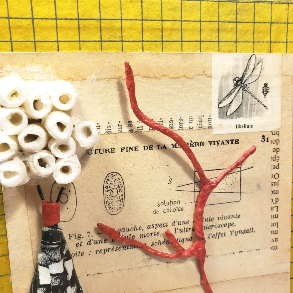 Détail du collage intérieur : insecte en relief rouge et callouts sur papier crème.