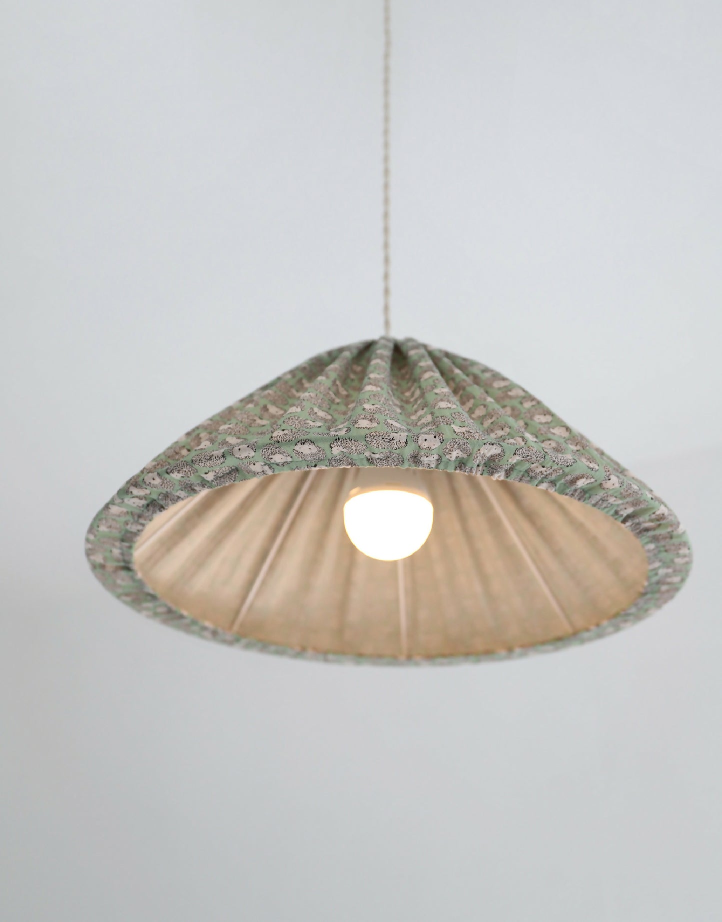 Suspension conique vert à motif hérissons, vue de dessous avec lumière allumée