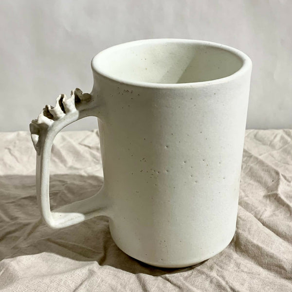 Tasse à thé blanche en céramique, anse sculptée sur le côté.
