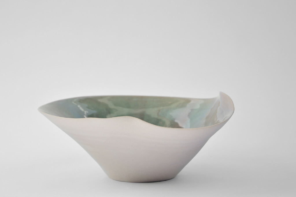 Coupe en céramique blanche à bord fin, intérieur vert marbré, forme ovale évasée.