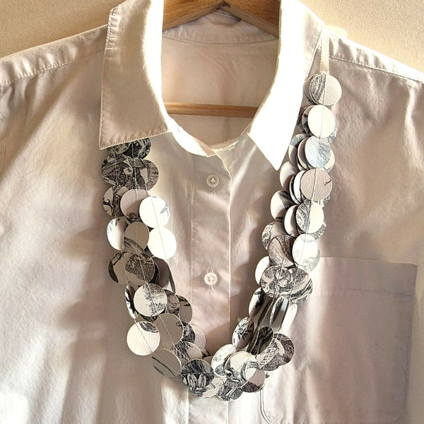 Collier en tissu à disques ronds noir, blanc et motifs floraux, sur chemise blanche