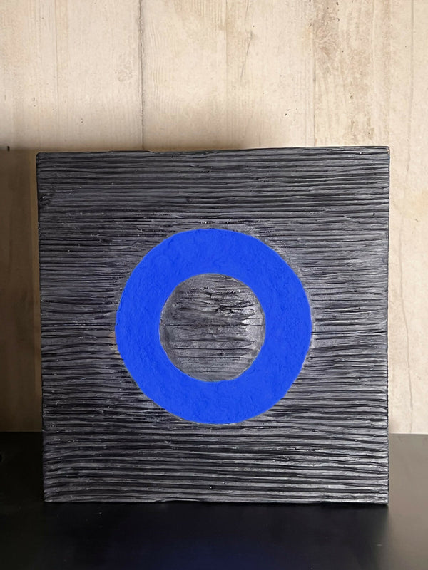 Panneau de sculpture en bois foncé avec cercle bleu au centre