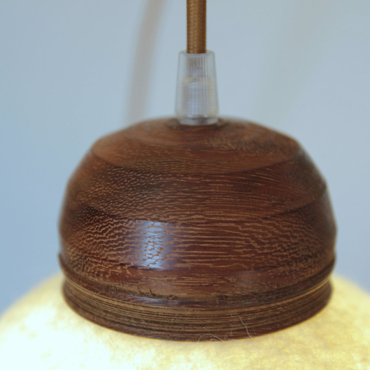 Lampe baladeuse : abat-jour rond en bois foncé texturé et douille transparente.