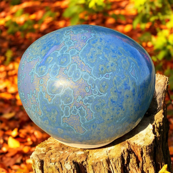 Pierre décorative ovale bleue veinée, motifs tourbillonnants et reflets nacrés.