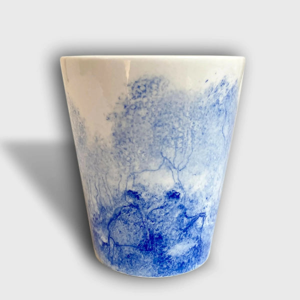 Gobelet en céramique blanc avec paysage bleu et silhouettes d’arbres peints