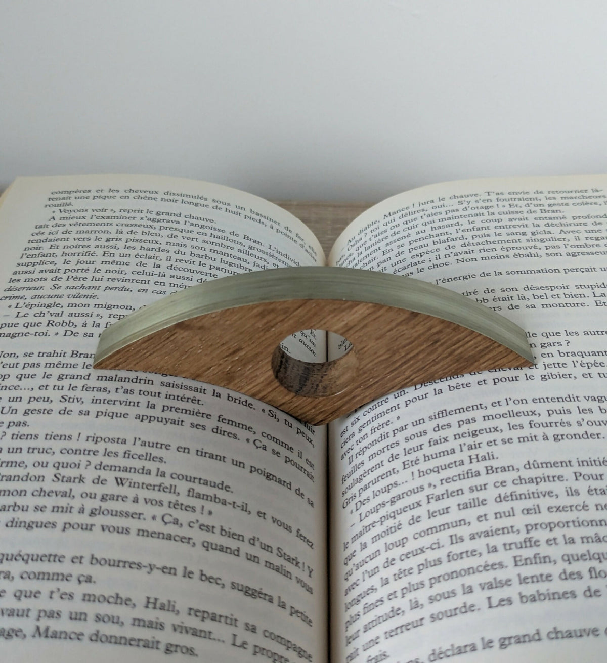 Bague de lecture kaki clair à marqueterie en bois, posée sur livre ouvert