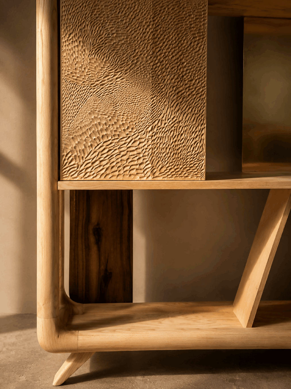 Bibliothèque en bois : panneau texturé et compartiment inférieur visible, pieds inclinés.