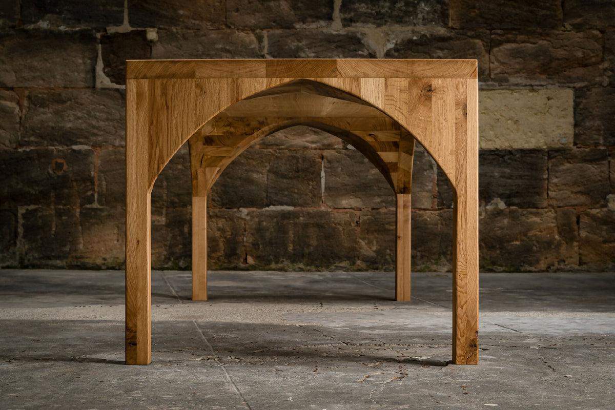 Table en bois avec piètement ajouré en arc, vue de face.