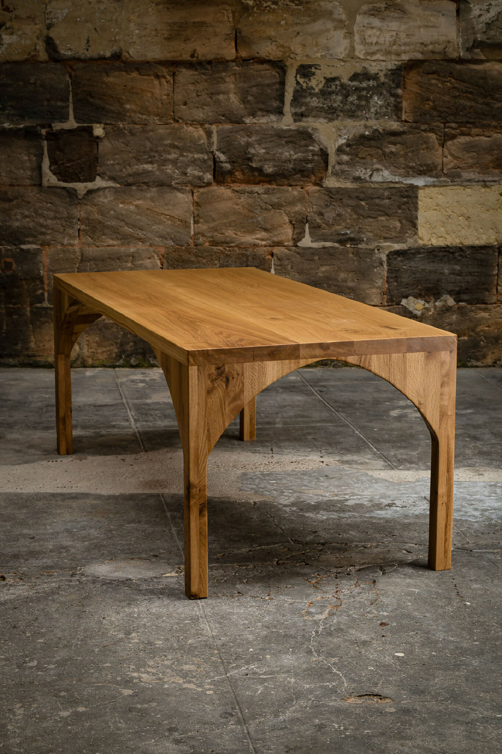 Table en bois avec piètement en arc et plateau rectangulaire, vue de trois-quarts.