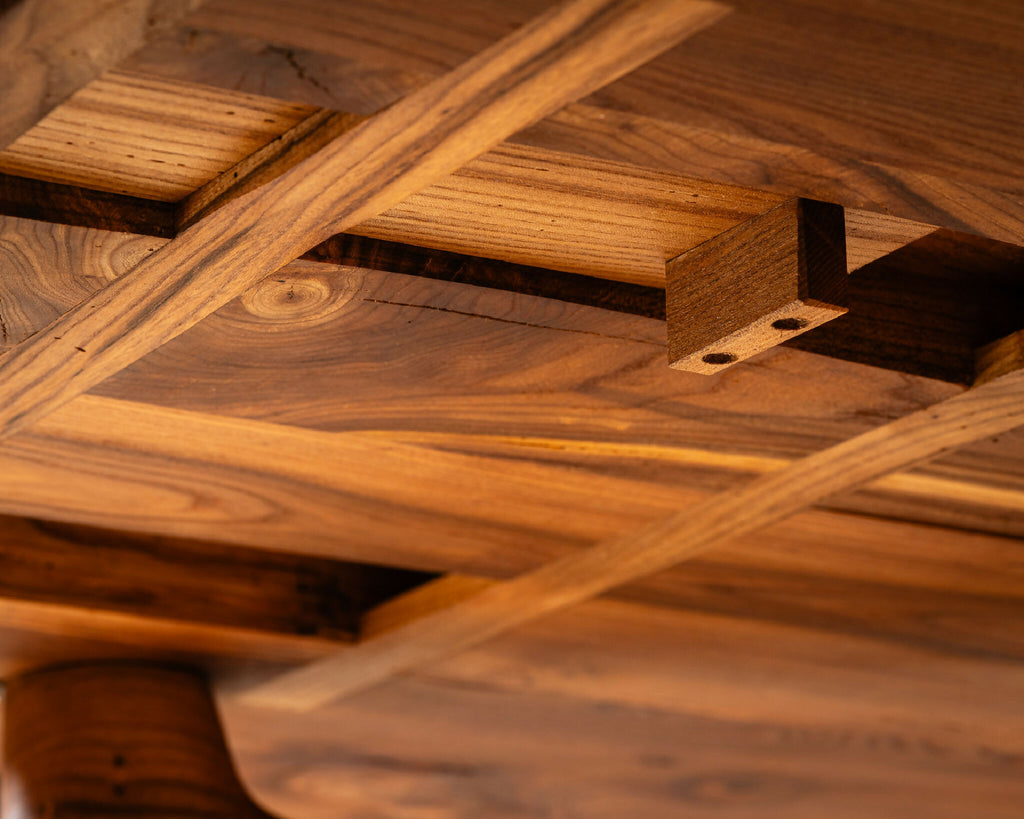 Table en bois massif, détail de l’entrecroisement des traverses sous le plateau.