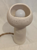 Lampe à poser champignon en céramique blanc cassé, globe lumineux visible à l’intérieur.