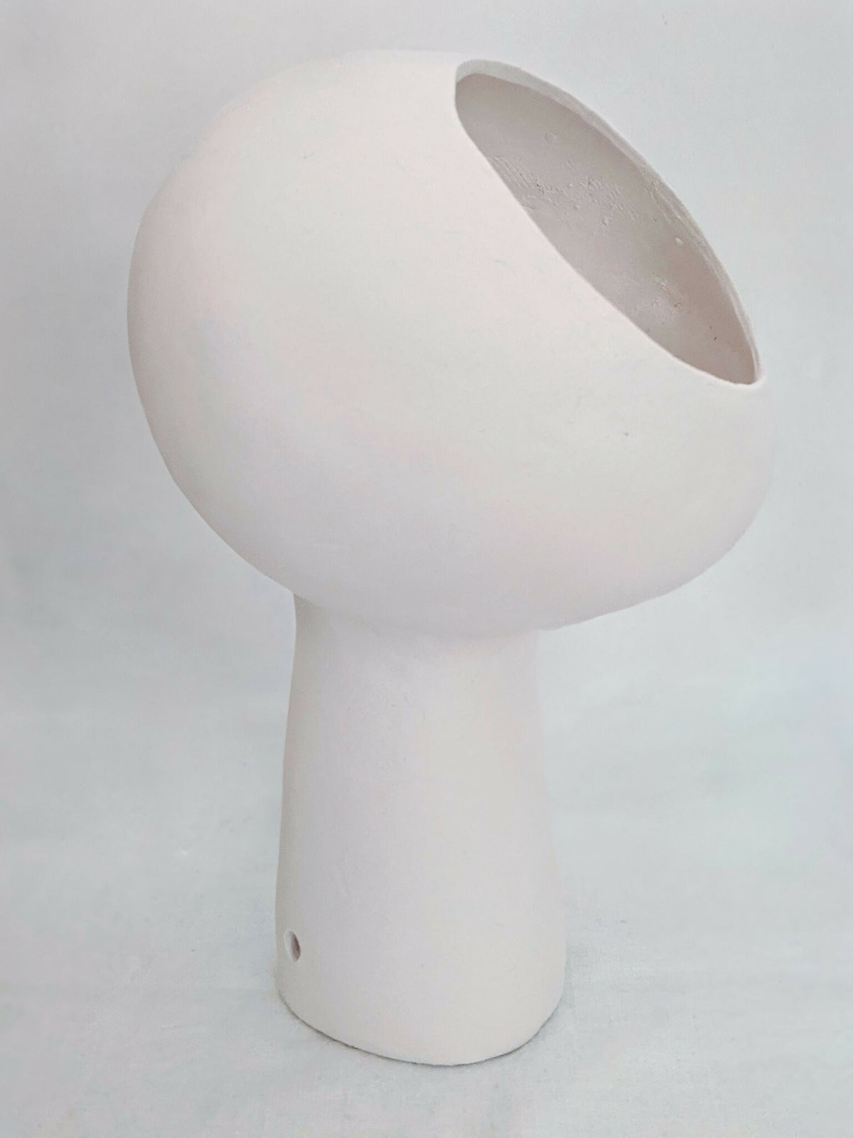 Lampe à poser design blanche, vue en biais, ouverture circulaire sur le dessus