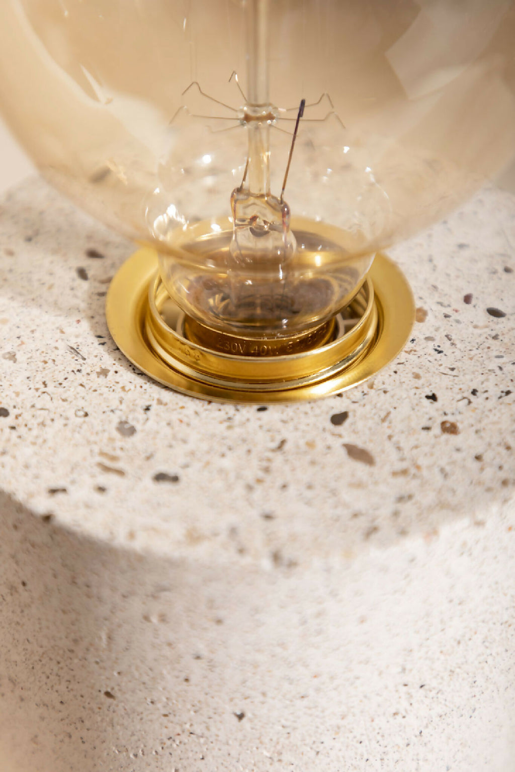 Lampe à poser : gros plan sur la base dorée et l’ampoule globe claire