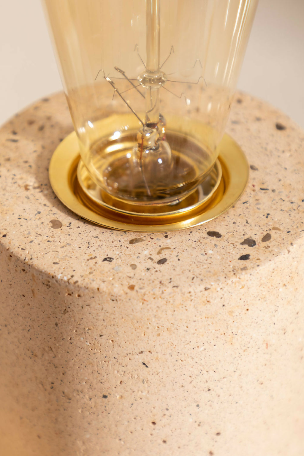 Lampe à poser avec socle rond beige texturé et base dorée autour de l’ampoule