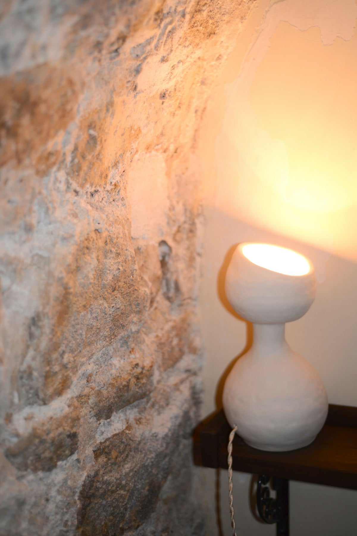 Lampe design blanche à deux globes, allumée sur une surface, éclairage doux
