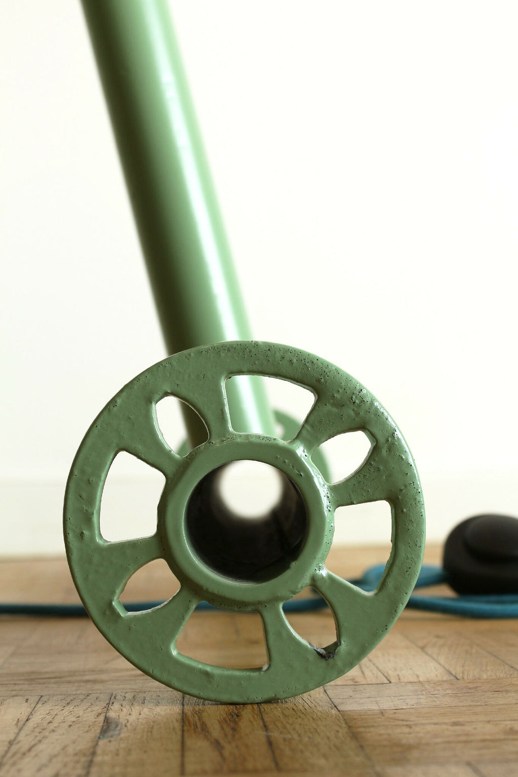 Lampe trépied vert, gros plan de la base à roues et du pied