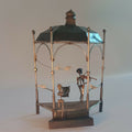 Cage de manège décorative en métal doré, toit noir et silhouettes peintes avec oiseaux.
