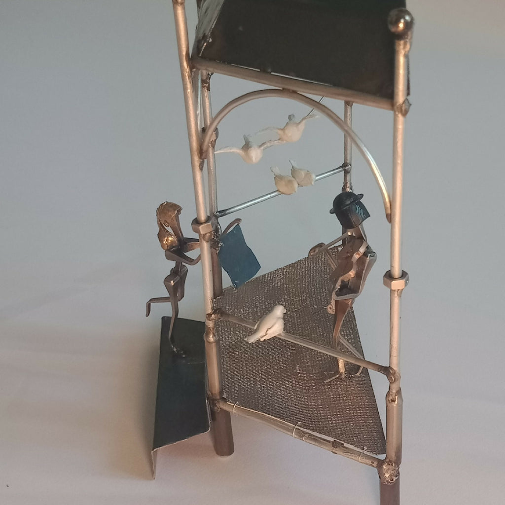 Manège décoratif avec figurines, barre arquée et oiseau en blanc en suspension.