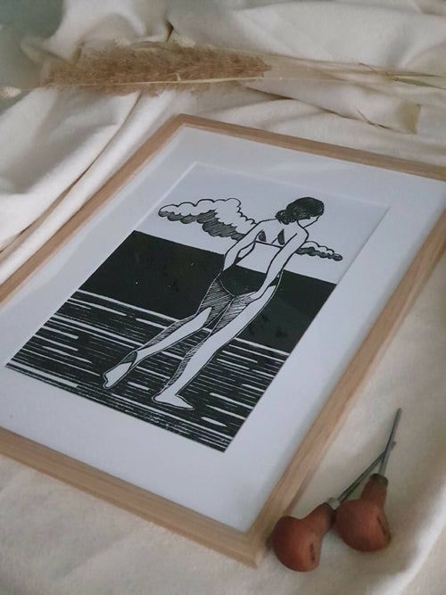 Affiche encadrée bois clair, illustration noir et blanc d’une femme au bord de l’eau.